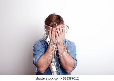 Young Man Attempts To Untangle A String Of Christmas Lights.