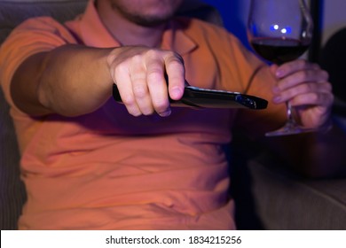 Young Man, Bachelor Sitting On A Couch, Drinking Wine  And Watching Movie, Series, Tv Show In The Late Evening, Night.