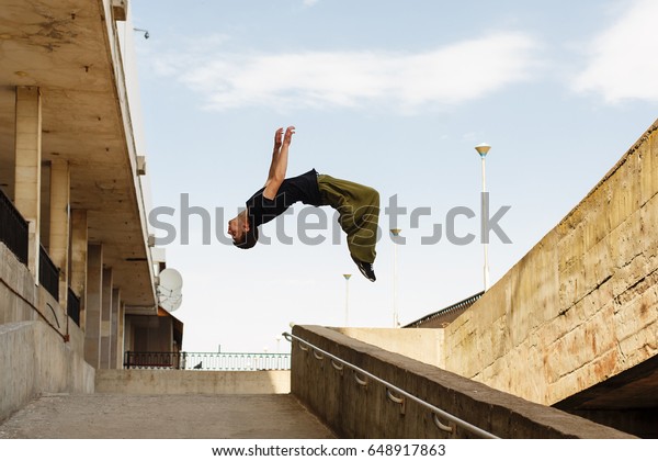 Young man back flip.\
Parkour in the urban space. Sport in the city. Sport Activities\
outdoors. Acrobatics