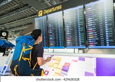 Young Man With Backpack In Airport Looking Flight Timetable