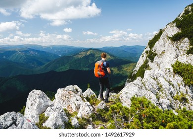 Young man with backpack hiking on the ridge of Piatra Craiului mountain, Romania, on a sunny day of summer - Shutterstock ID 1492617929