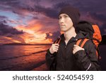 Young man with backpack on the background of sea sunset.