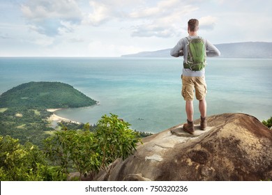 Young Man With A Backpack Overlooking A Tropical Bay