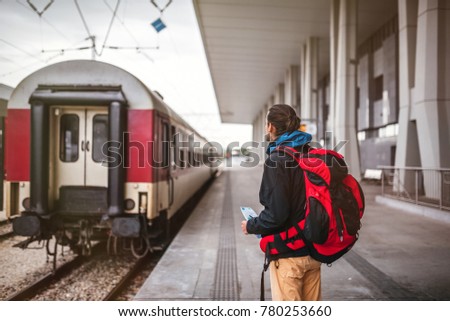 Young man with a backpack ready for a trip with a train. Wanderlust concept