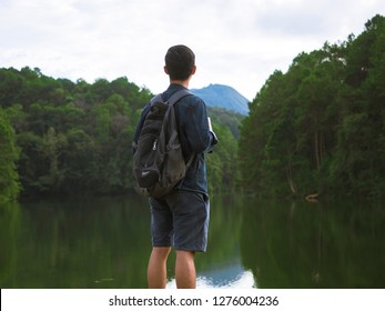 Young man backpack standing front of lake and valley background in natural,Traveler man look at mountain and lake.