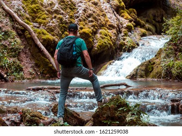 Young man with backpack standing on waterfall cliff in summer mountains and enjoying view of nature. Mountain river in Caucasus mountains. Hiking training. Dilijan, Armenia - Powered by Shutterstock