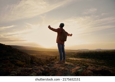 Young man with backpack standing on mountain with hands outstretched - Powered by Shutterstock