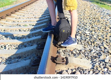 A young man with a backpack waiting for the train stands on the railway tracks
