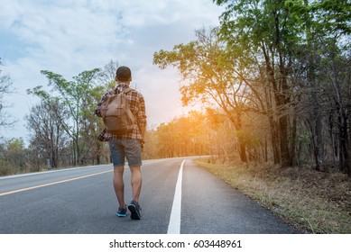 Young Man With Backpack Walking Alone On The Road On The Mountain.hot Sun.