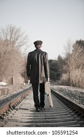 Young Man Backward With Hat And Old Open Suitcase In Rail Way