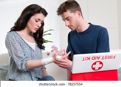 Young Man Bandage His Girlfriend With First Aid Kit At Home After An Injury