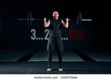 Young Man With Barbell Flexing Muscles And Making Shoulder Press Lunge In Gym