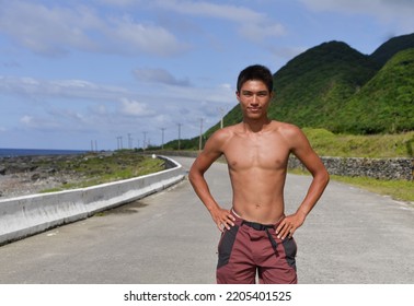 Young Man Bare-chested Man  Standing On The Beach Barefoot. Scenic Ocean View, Morning Photo, Wearing Brown Jeans.