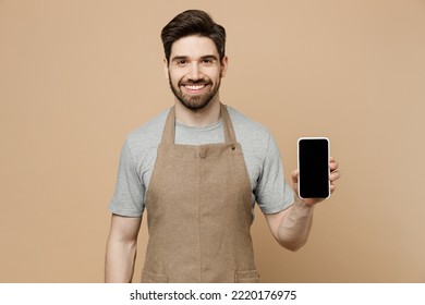 Young man barista barman employee wear brown apron work in coffee shop use mobile cell phone blank screen workspace area isolated on plain pastel light beige background Small business startup concept - Powered by Shutterstock