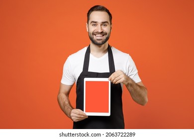 Young man barista bartender barman employee wear black apron white t-shirt work in coffee shop using tablet pc computer blank screen workspace area isolated on orange background Small business startup - Powered by Shutterstock