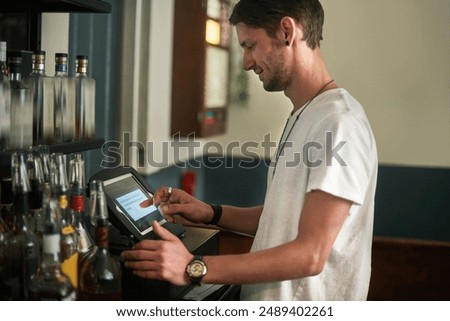 Young man, bartender and order with pos system for receipt, checkout or register in liquor store. Male person or happy barman working on tablet screen for service, payment or checking transaction