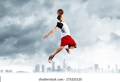 Young man basketball player with ball in hands jumping high