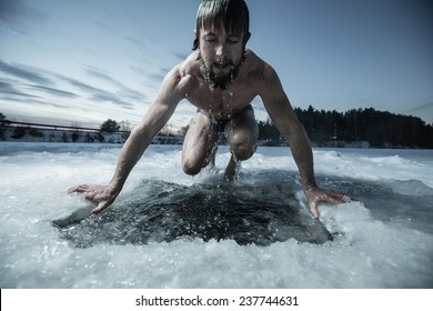 Young man bathing in the ice hole