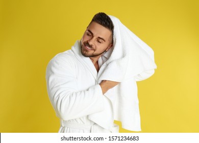 Young Man In Bathrobe Drying Hair With Towel On Yellow Background