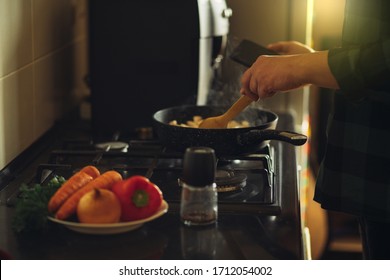 Young Man With Beard Cooking Dinner And Using His Smart Phone At The Kitchen.