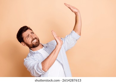Young man with a beard gesturing expressively with hands against beige background