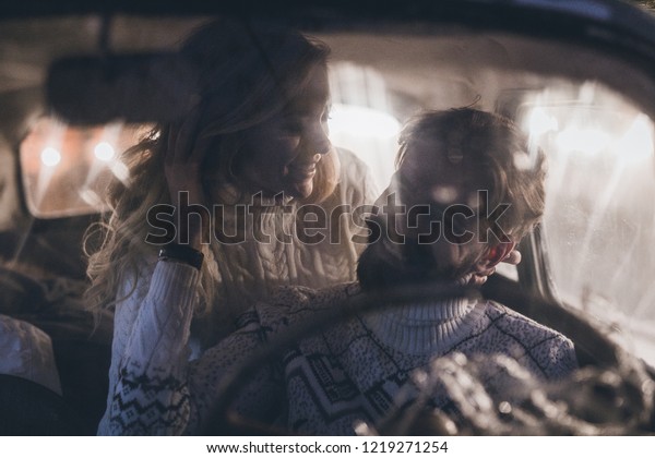 Young man with beard and his\
girlfriend in vintage car with pine tree celebrating\
Christmas