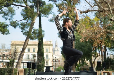 Young Man With Beard And Ponytail, Wearing Black Shirt With White Polka Dots And Black Pants And Jacket, Dancing Flamenco On A Stage. Concept Art, Dance, Culture, Tradition.