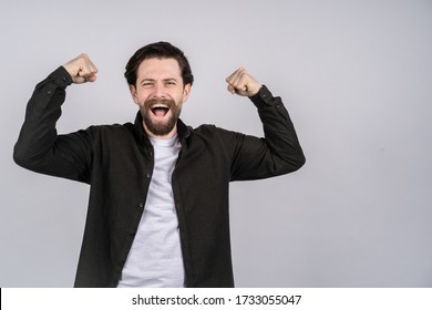 Young man with beard showing a gesture of power, he cheerfully laughs.