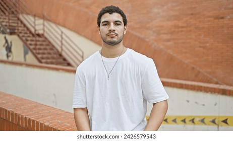 A young man with a beard stands on a city street with a casual demeanor. - Powered by Shutterstock