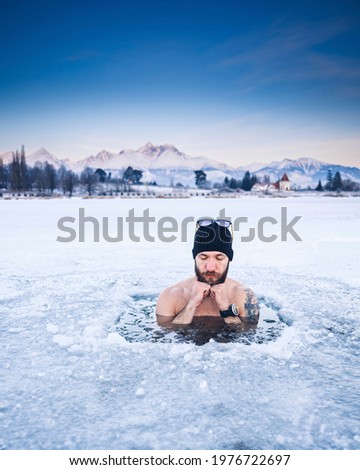 Young man with beard swims in the winter lake. Winter swimm.