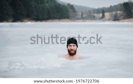 Young man with beard swims in the winter lake. Winter swimm.