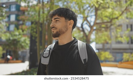 A young man with a beard walks thoughtfully through a sunlit urban park, embodying a casual, stylish demeanor. - Powered by Shutterstock