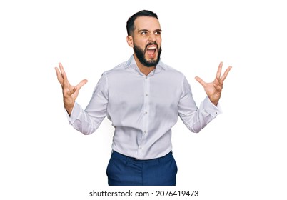 Young man with beard wearing business shirt crazy and mad shouting and yelling with aggressive expression and arms raised. frustration concept. 