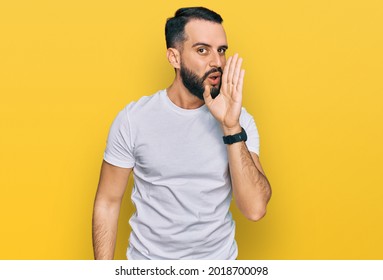 Young Man With Beard Wearing Casual White T Shirt Hand On Mouth Telling Secret Rumor, Whispering Malicious Talk Conversation 