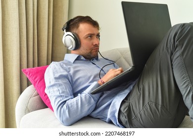 Young Man Beat Maker Working From Home With His Laptop Laying On Couch