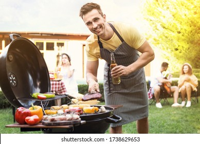 Young man with beer cooking on barbecue grill outdoors