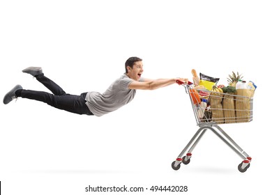 Young Man Being Pulled By A Shopping Cart Full Of Groceries Isolated On White Background