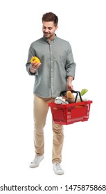 Young Man With Bell Pepper And Shopping Basket Full Of Products Isolated On White