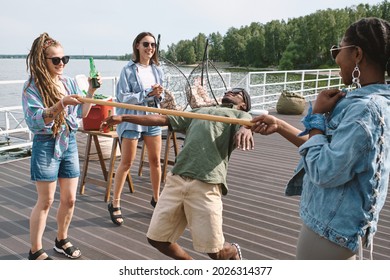 Young Man Bending Backwards To Walk Under Vertical Bar In Hands Of His Friend To Win Limbo Game