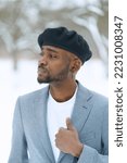 Young man in beret like Che Guevara stay on winter background. African american hold jacket looking aside. High quality photo