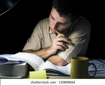 Young Man Biting Pencil Studyng at Night isolated on black background - Powered by Shutterstock