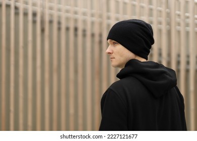 Young man in a black beanie hat and hoodie on a wooden background. - Powered by Shutterstock