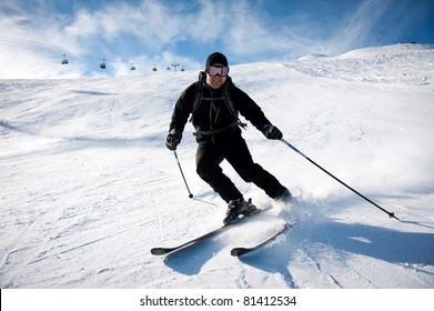 Young Man In Black Clothing Skiing On Mountain Slope At Ski Resort