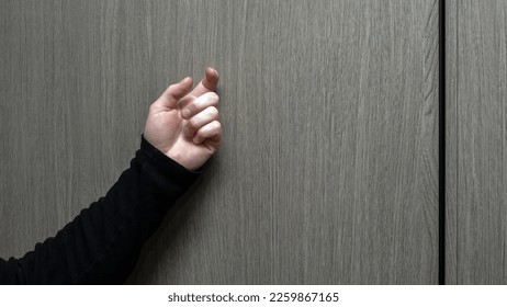 A young man in a black jacket knocks on the door. A visit to someone's home. Knock on the wooden door. Lifestyle