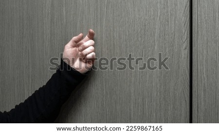A young man in a black jacket knocks on the door. A visit to someone's home. Knock on the wooden door. Lifestyle