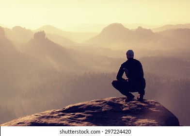Young man in black sportswear is sitting on cliff's edge and looking to misty valley bellow. Autumn landscape. Foggy mountain.Person look. Man hike.Cliff edge. Climbing adventure.Guy look.Foggy valley - Shutterstock ID 297224420