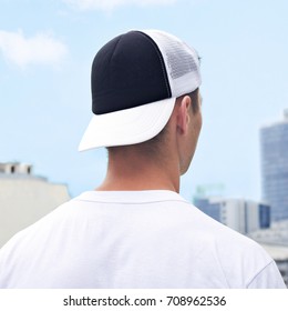 Young man in a black and white trucker hat and white t-shirt. Trucker hat mock up. Baseball cap template