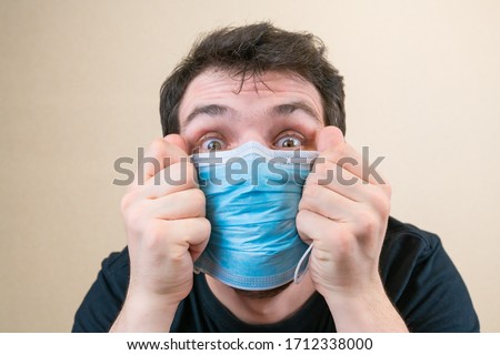 Young man in blue protective medical mask and happu with it. Self-isolation and quarantine. Stay home