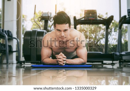 Young man bodybuilder doing push up in fitness center. Healthy lifestyle and body building concept.