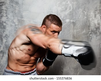 Young man in boxing gloves making punch  - Powered by Shutterstock